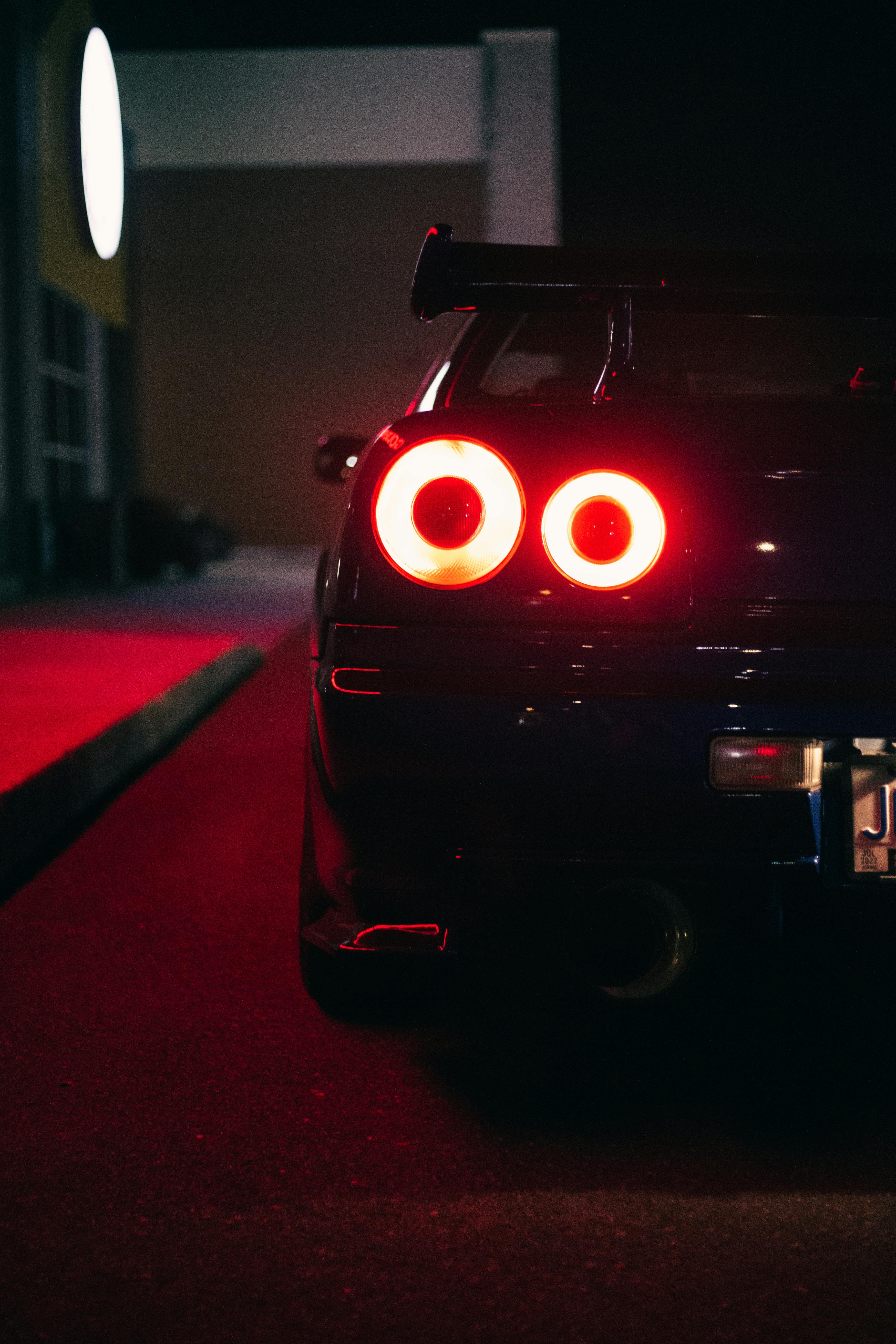 A tight, glowing close-up of the iconic round red taillights of a Nissan Skyline GT-R at night.