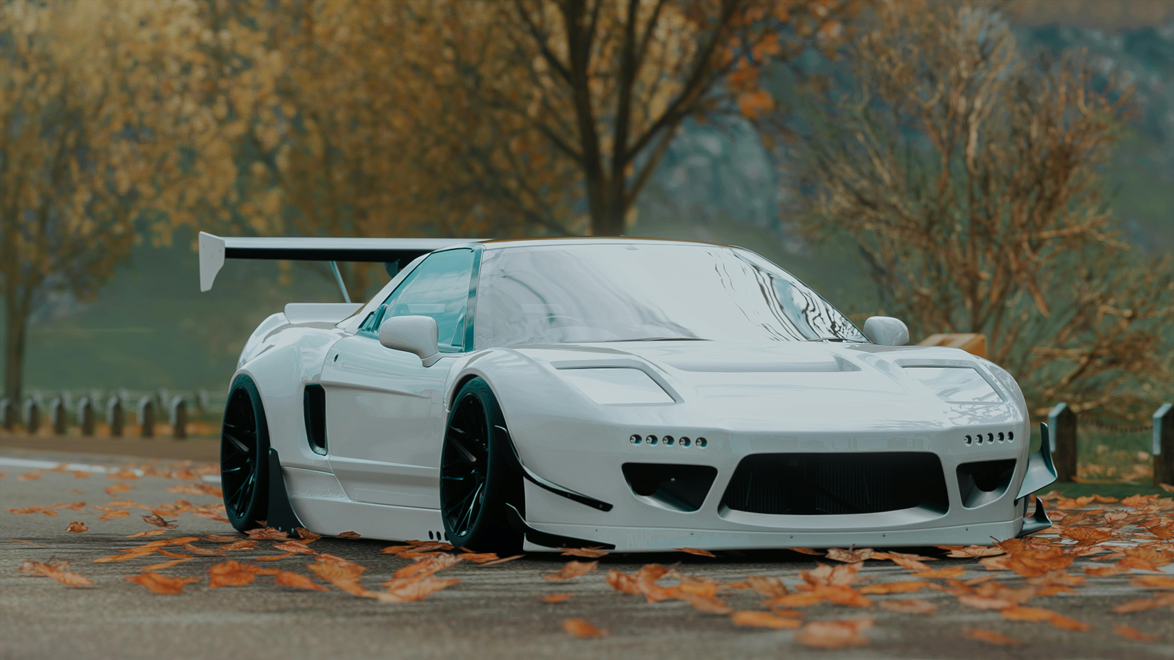 A front-three-quarter view of a modified white Honda NSX featuring a custom body kit, sitting low on a leaf-strewn road.