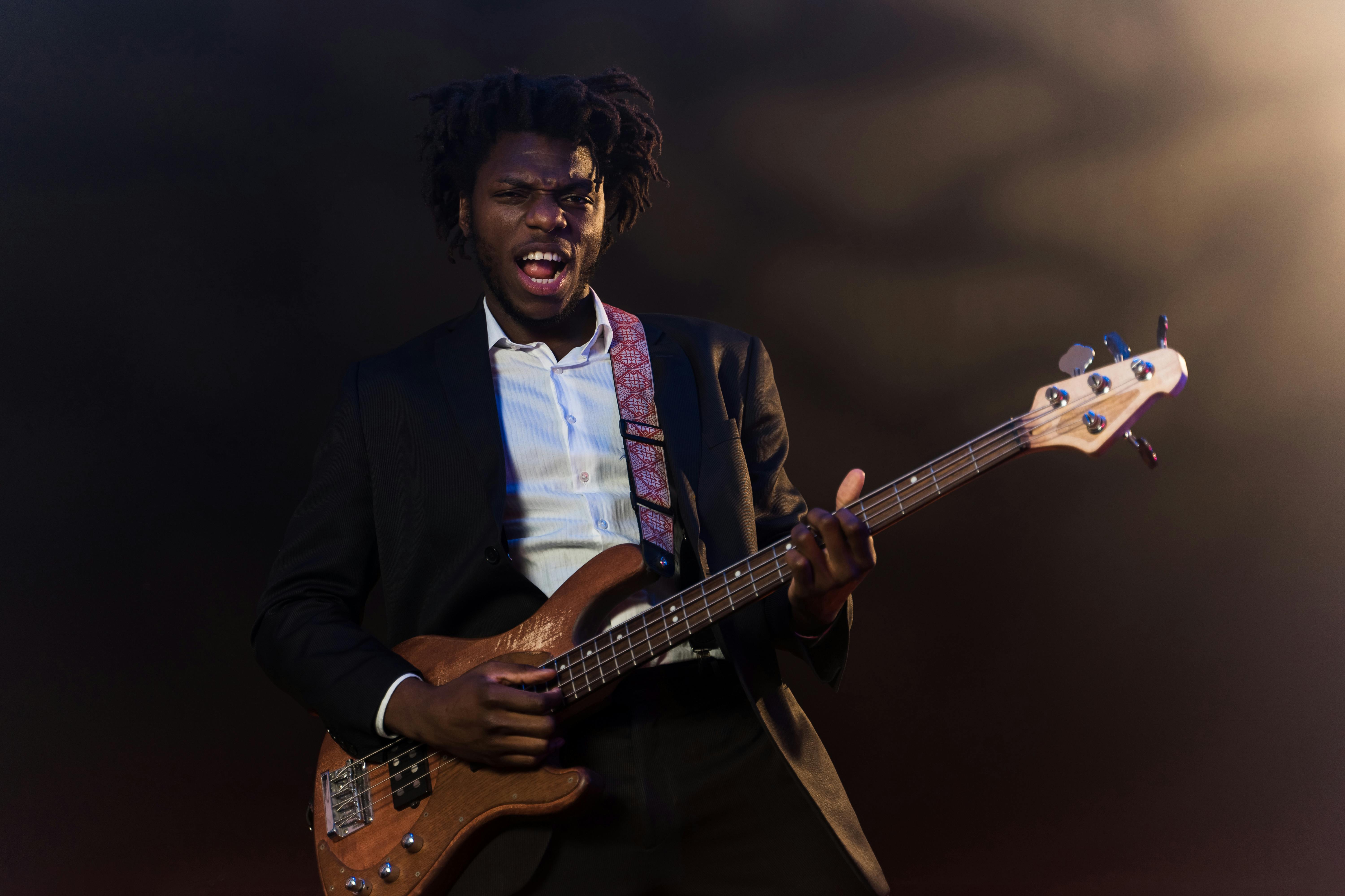 A joyful shot of the same bassist, singing and smiling while performing under stage lights.