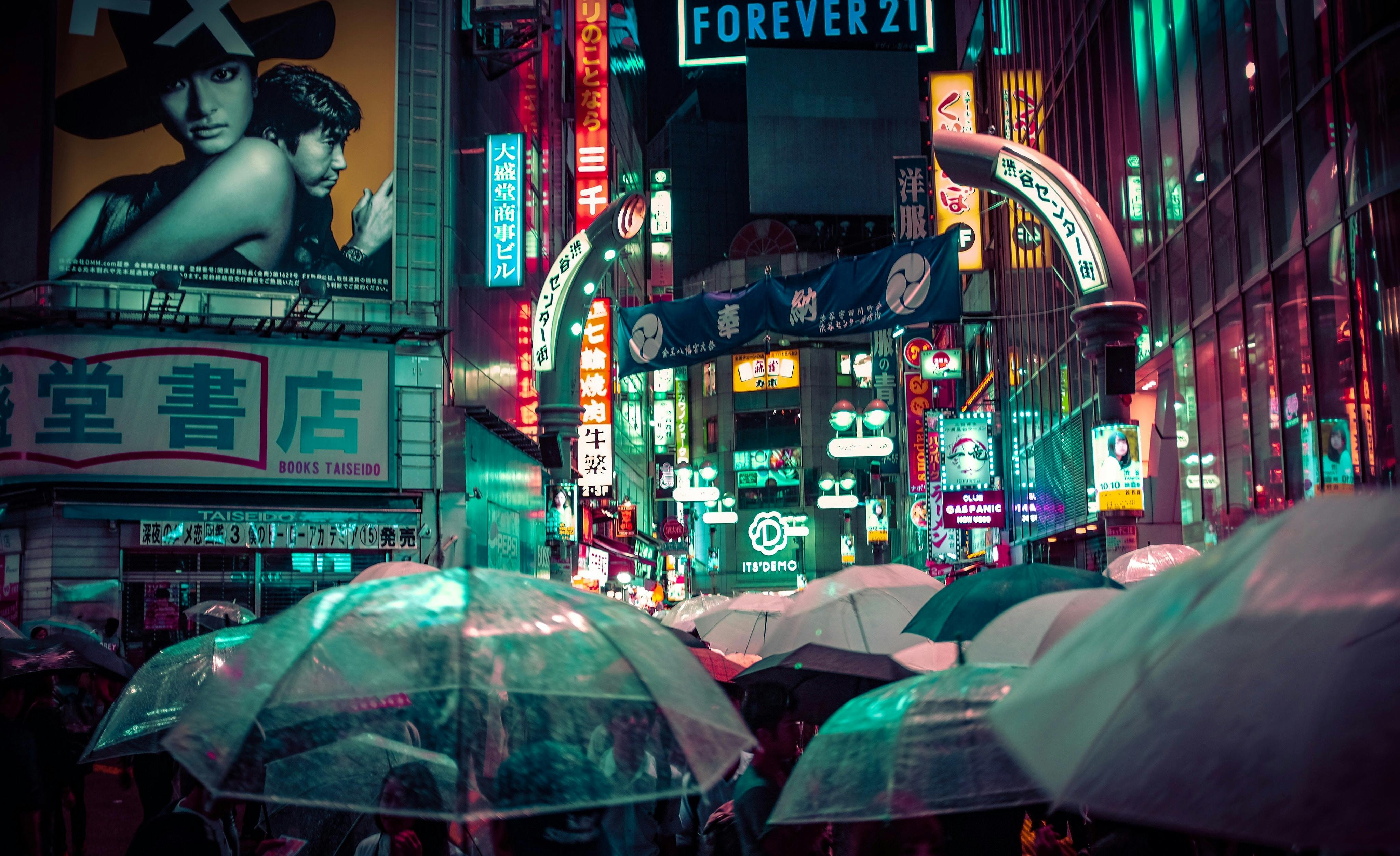 Neon-lit Tokyo street at night with umbrellas and glowing shop signs