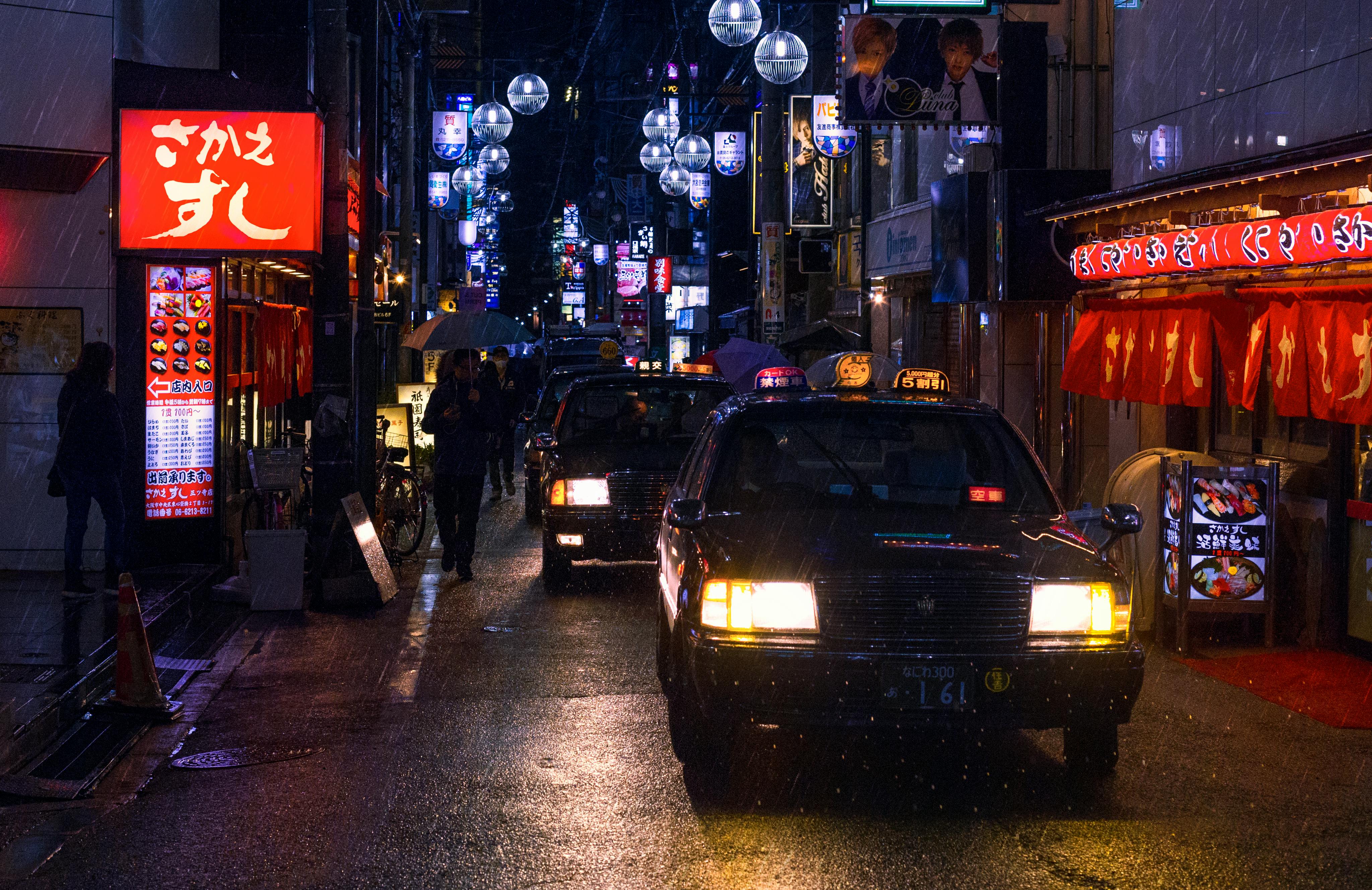 Rainy Tokyo alleyway at night with neon signs and taxi headlights