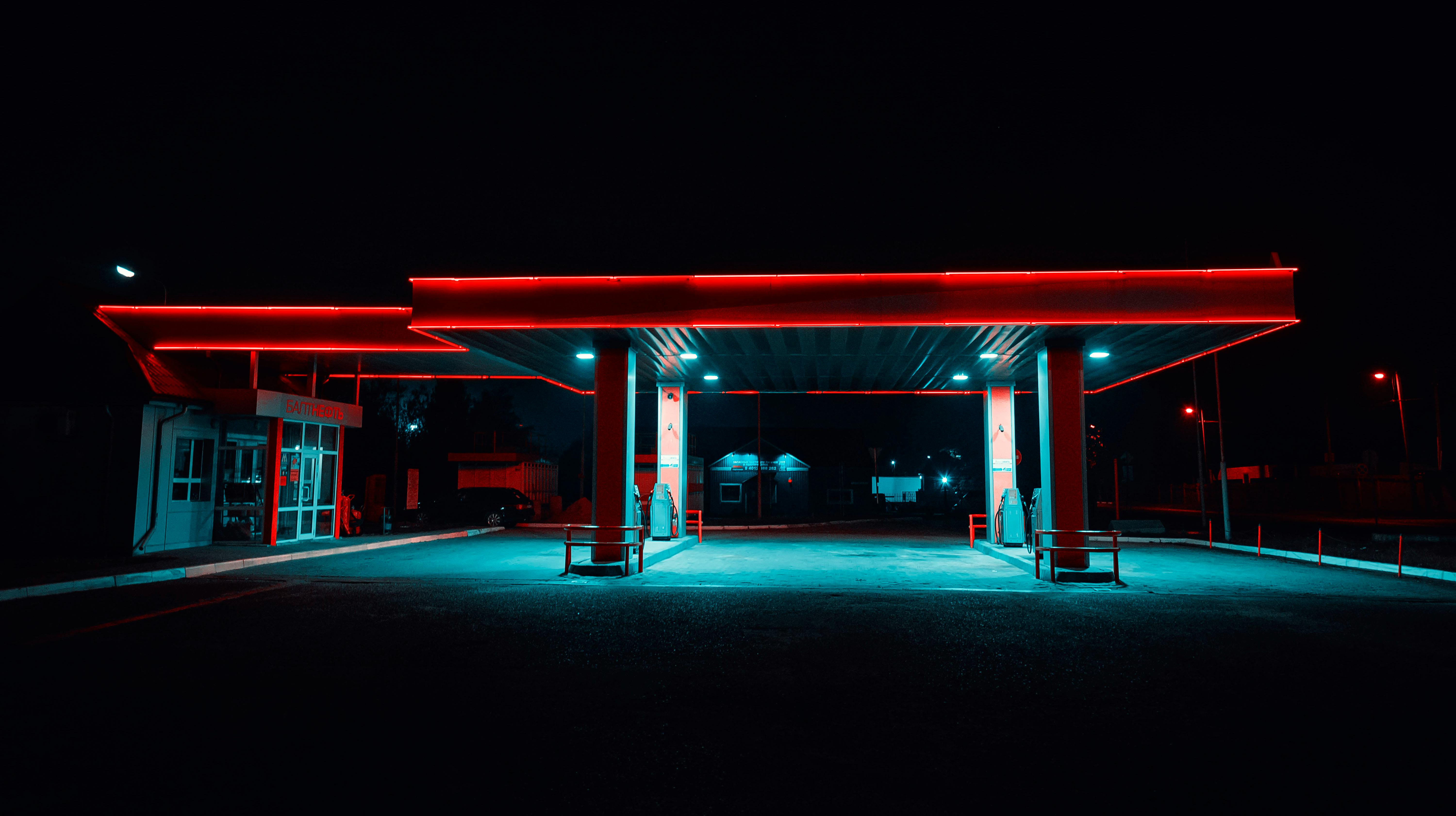 Empty petrol station lit in red and cyan neon at night