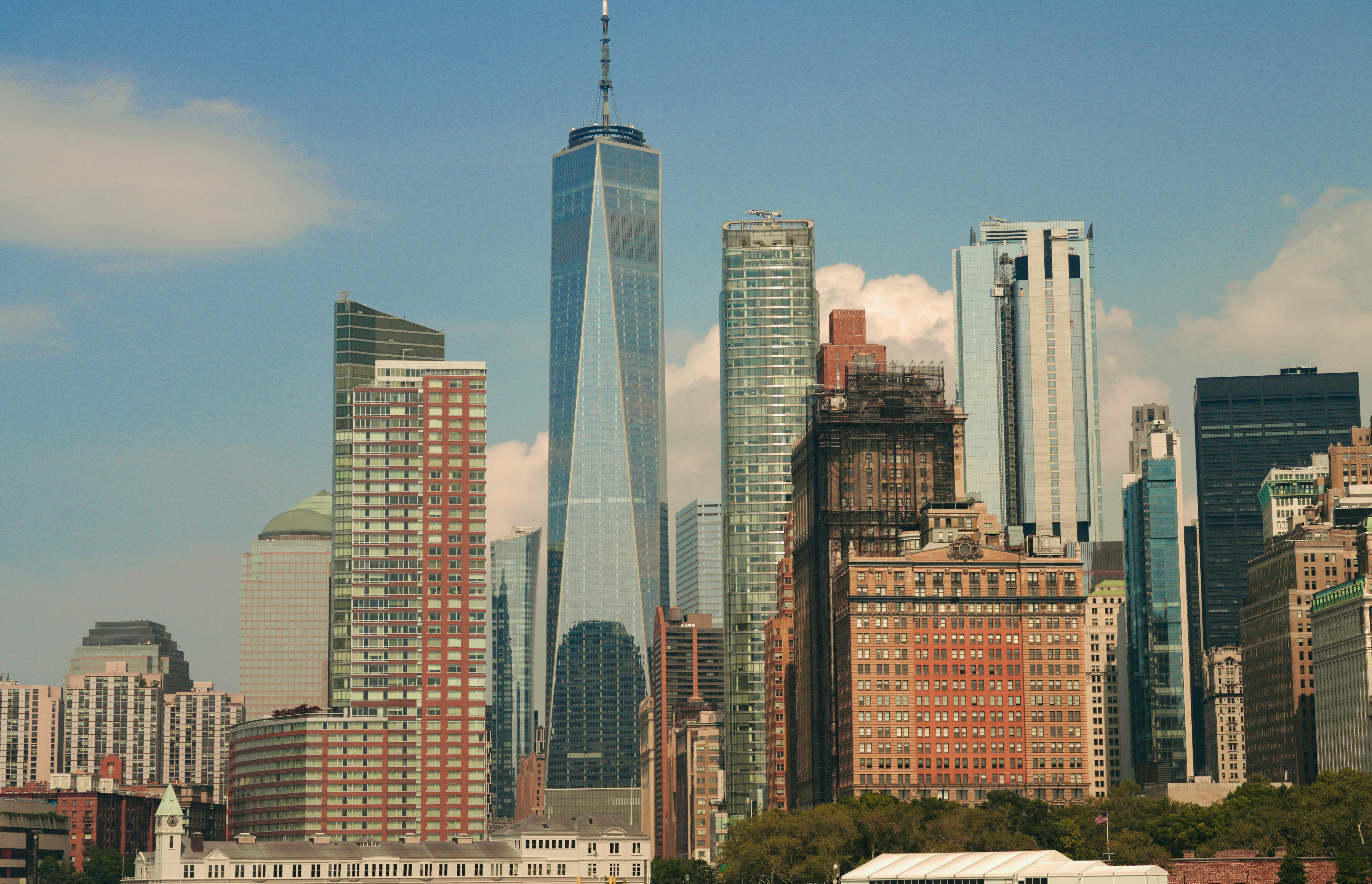 Clear daytime view of the skyscrapers in Lower Manhattan, featuring the prominent glass facade of One World Trade Center.