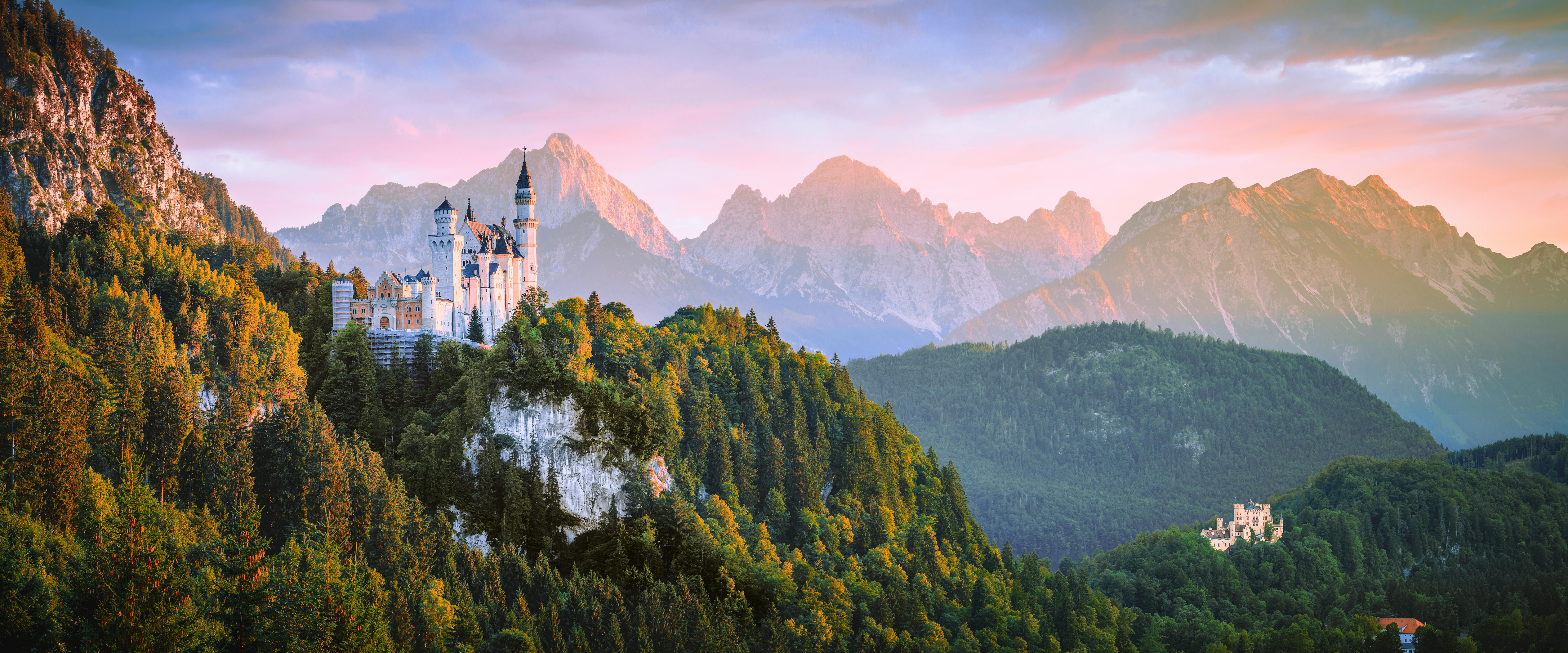 Neuschwanstein Castle perched on a forested hillside at golden sunset