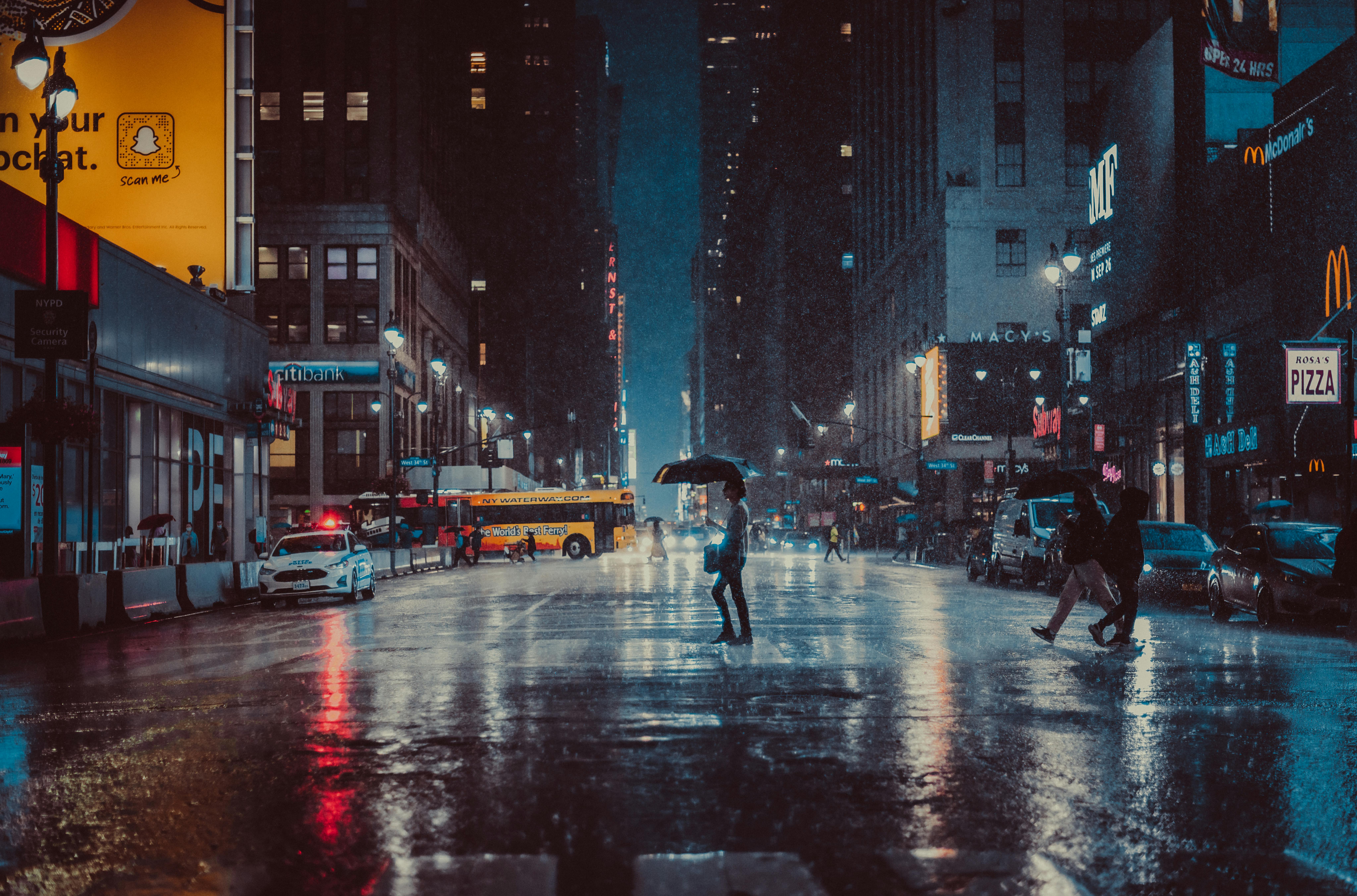 People crossing a rainy New York City street at night