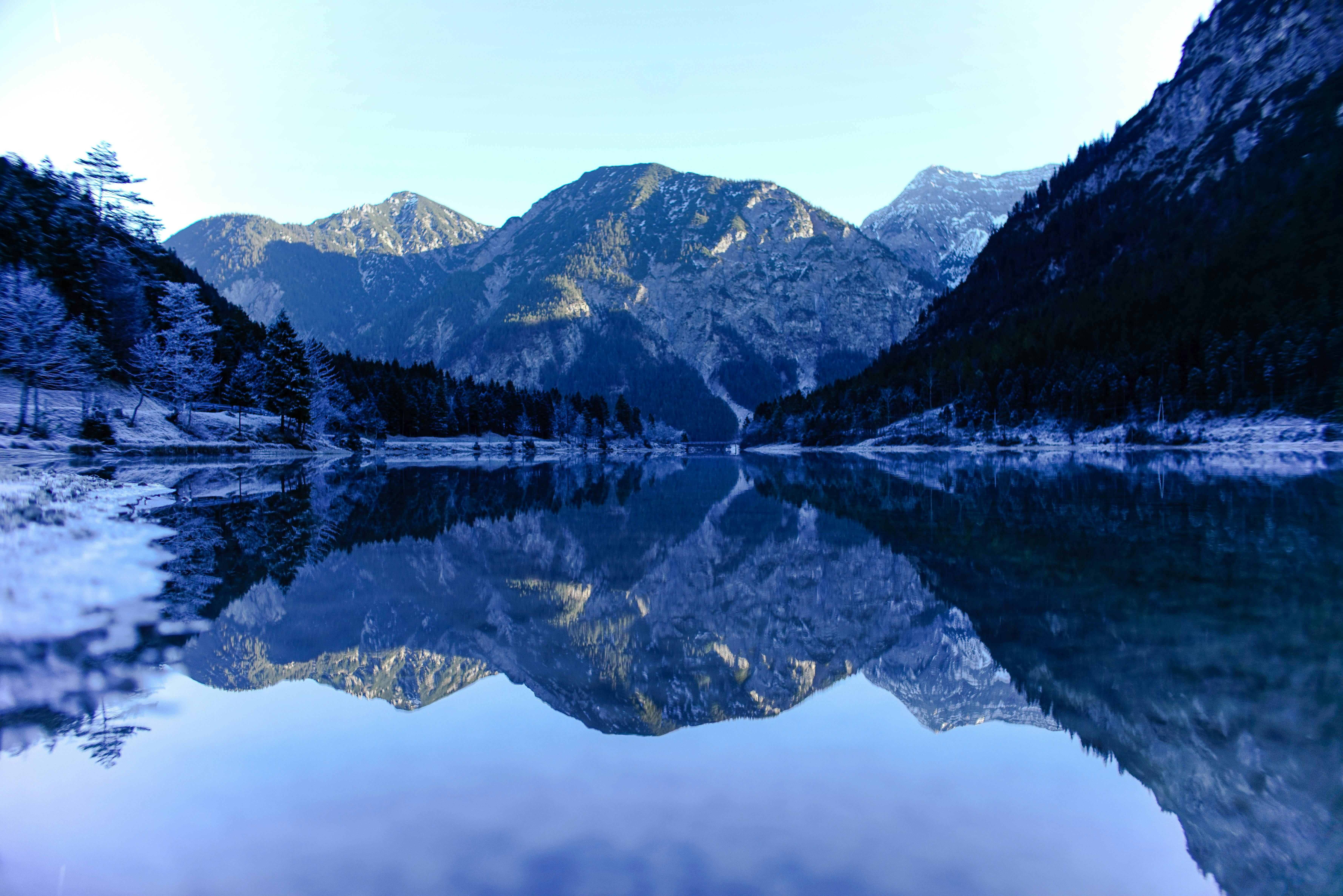 Snowy mountain peaks perfectly reflected in the crystal-clear, still water of a mountain lake.